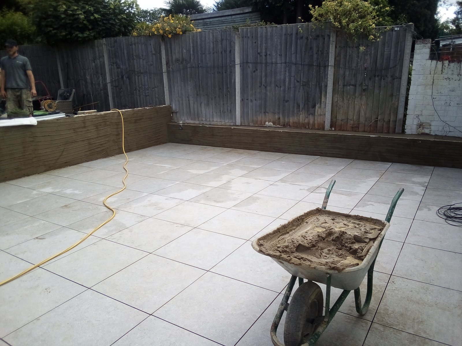 Light porcelain patio and white rendered retaining walls in a compact Surbiton garden